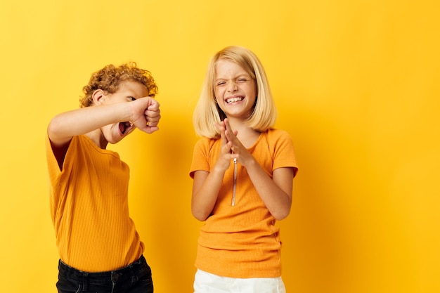 Jongen en meisje vrijetijdskleding spelletjes leuk samen poseren op gekleurde achtergrond