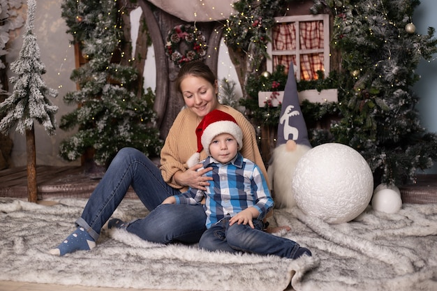 Jongen en moeder dichtbij Kerstboom thuis