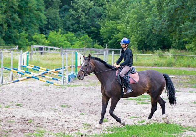 Jongen en paard Paardrijden Jumping Sportmanjongen op een bruin paard doorbreekt een barrière