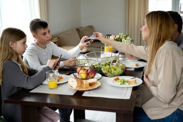 Jongen eten met smartphone zijaanzicht