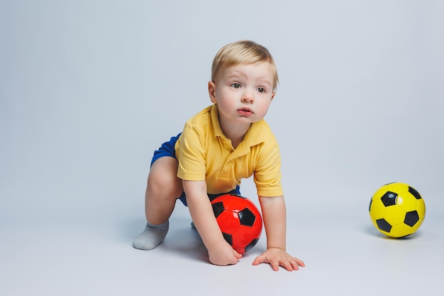 Foto jongen fan met een voetbal in zijn handen geïsoleerd op een witte achtergrond newbie kind in voetbal sport voor kinderen kleine atleet gele en blauwe voetbal kit voor kinderen