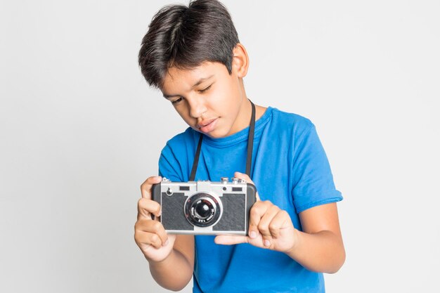 Jongen fotografeert door middel van een camera terwijl hij tegen een grijze achtergrond staat