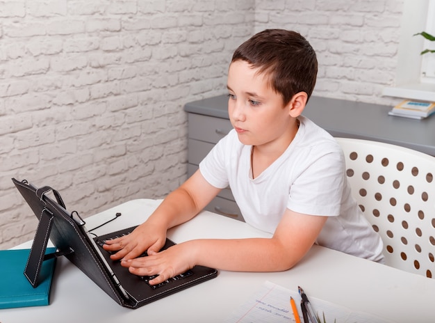 Jongen gebruikt digitale tablet voor videogesprek met zijn leraar. thuisonderwijs