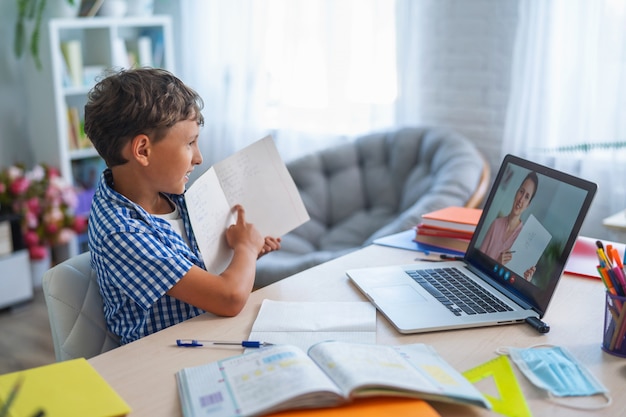 Jongen gebruikt laptop om een videogesprek met zijn leraar te voeren