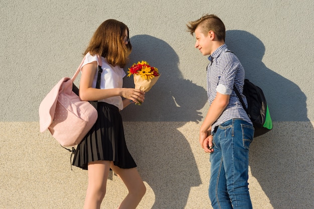 Jongen geeft meisje boeket bloemen. Outdoor Portret van paar tieners.