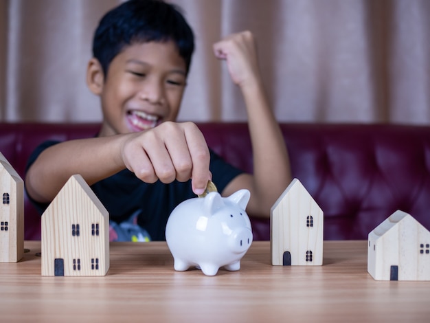 Jongen geld besparen in een wit varken spaarvarken. Besparing concept. Sparen voor de toekomst.