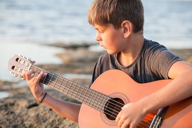 Jongen gitaar spelen door de oceaan.