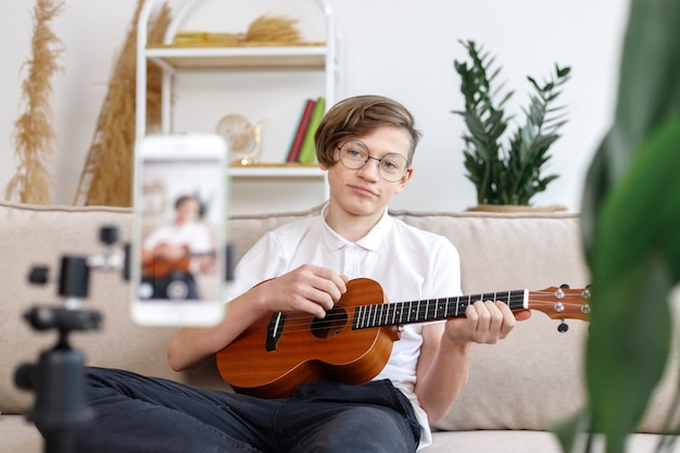 Jongen gitaarspelen en les op video opnemen thuis