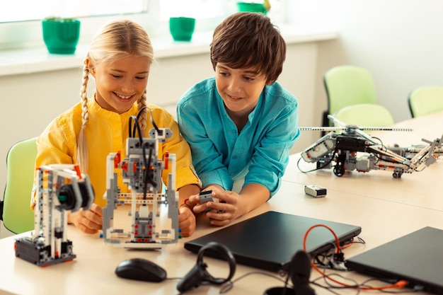 Jongen helpt zijn klasgenoot een robot aan te zetten