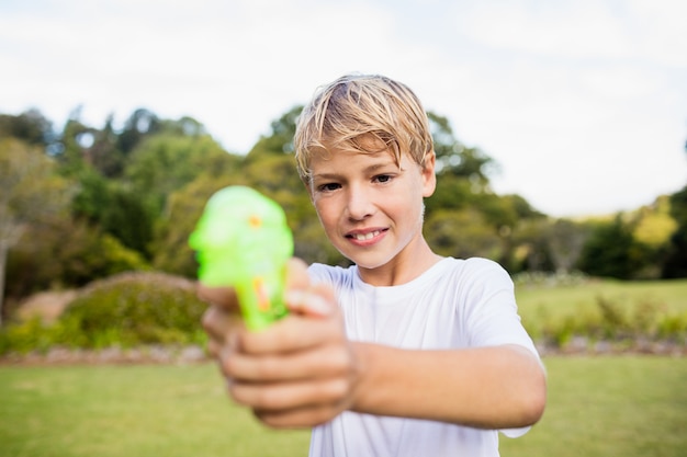 Jongen het stellen tijdens een zonnige dag met zijn waterkanon