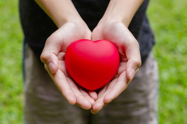 Jongen houdt een hart in zijn handen, een jongen met een rood hart in zijn handen. valentijnsdag concept.