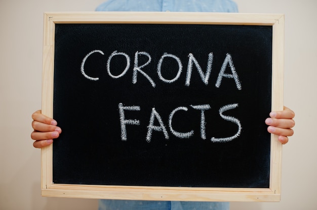 Jongen houdt inscriptie op het bord met de tekst Corona facts