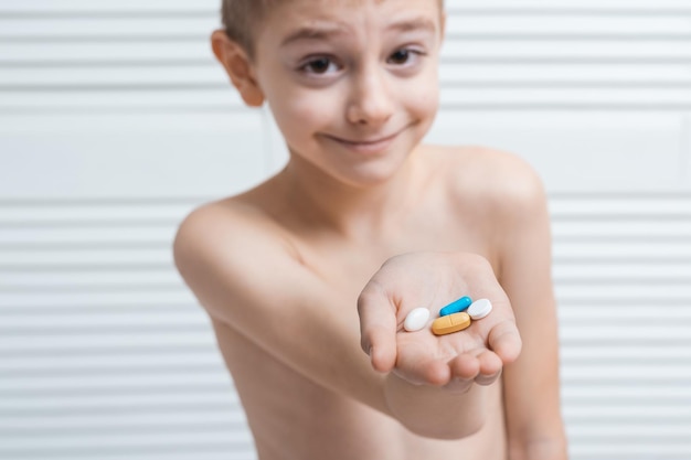 Jongen houdt tablet op handpalm en glimlacht Gezondheidsvitamines voor kinderen voor kinderen