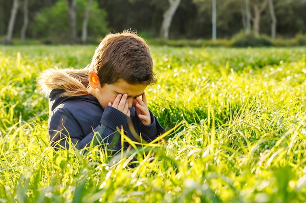 Foto jongen huilt terwijl hij in het gras zit.