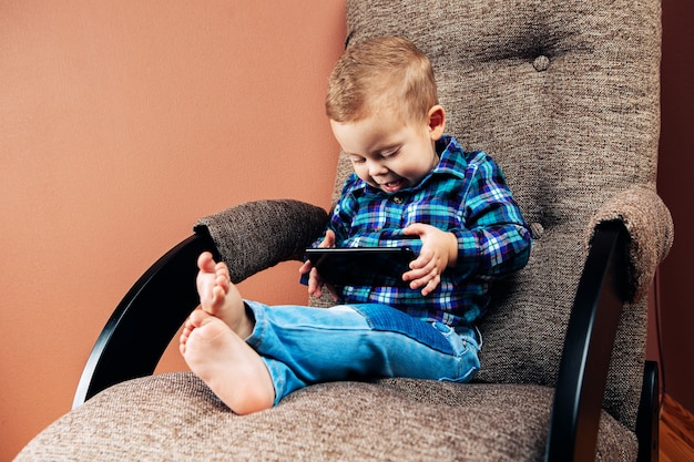 Jongen in bed zitten en spelen met mobiele telefoon