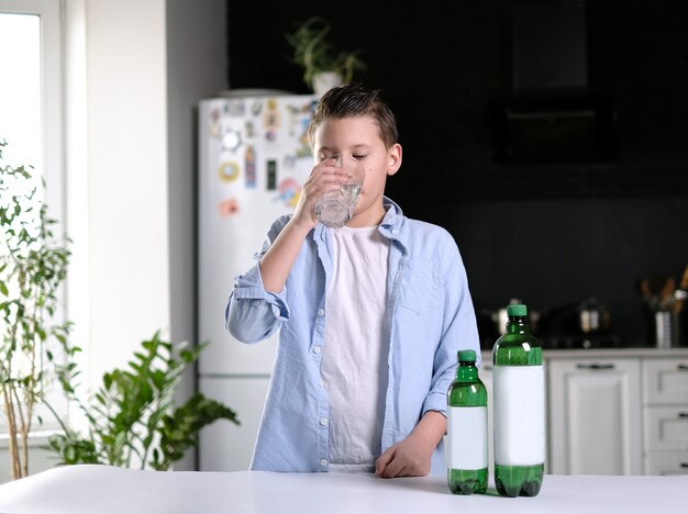 Jongen in blauw t-shirt drinkwater in de keuken