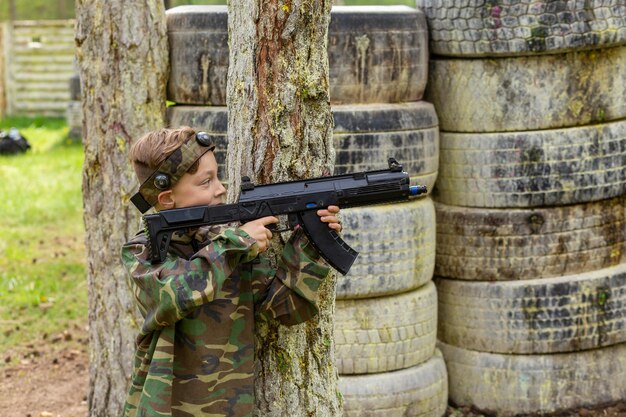 Jongen in camouflage die lasergame speelt in een speciale bosspeeltuin