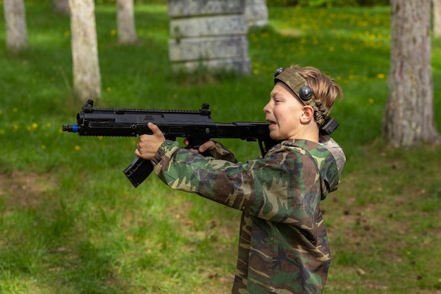 Jongen in camouflage die lasergame speelt in een speciale bosspeeltuin