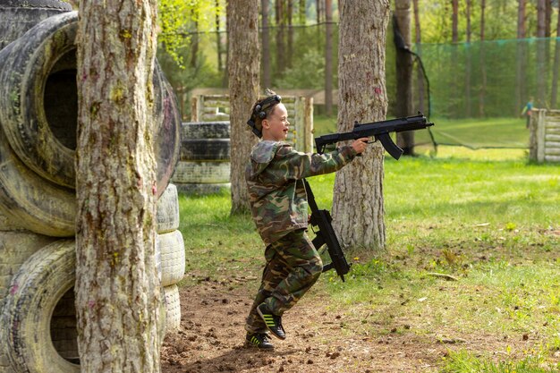 Jongen in camouflage die lasergame speelt in een speciale bosspeeltuin