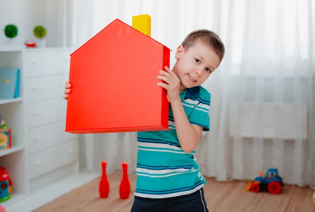 Jongen in de kinderkamer met een rood speelgoedhuis