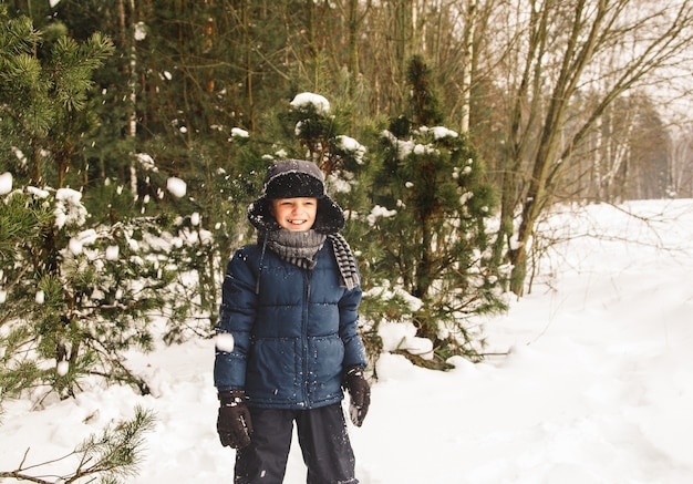 Jongen in de winter bos staat