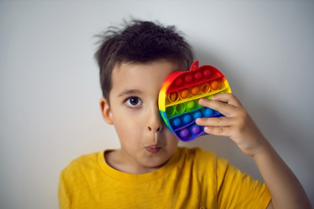 Jongen in een geel t-shirt speelt een modespelletje pop het in de vorm van een siliconen appel