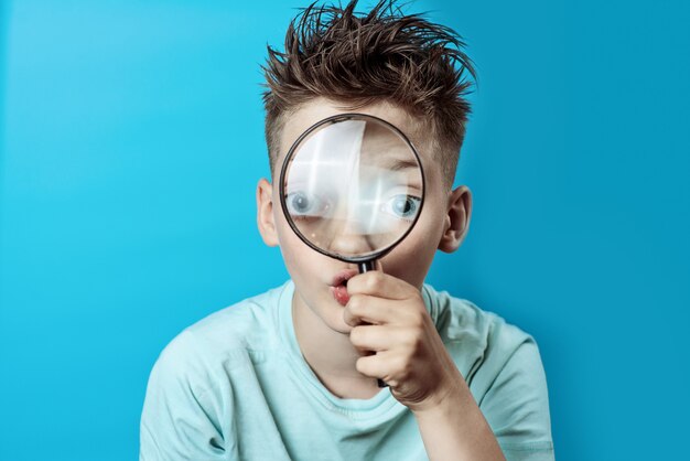 Jongen in een lichte t-shirt op zoek naar een groot vergrootglas