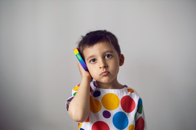 Jongen in een shirt met kleurrijke cirkels speelt met een siliconen pop-it-speeltje