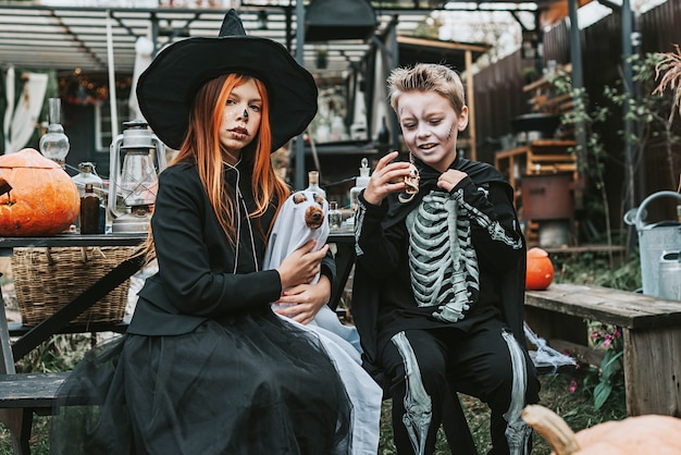 jongen in een skeletkostuum en een meisje in een heksenkostuum met hond in een spookkostuum Halloweenfeest