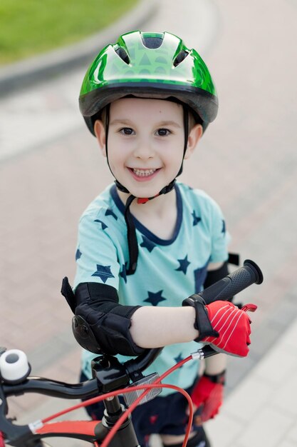 Jongen in groene helm rijden op zijn eerste fiets in het zomerpark