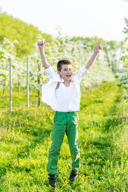 Jongen in het bloeiende tuin springen