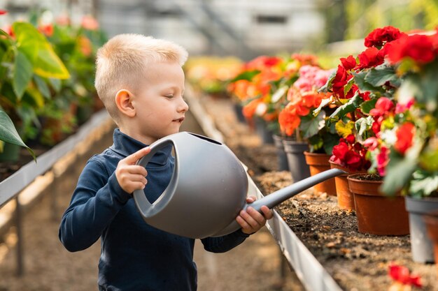 Jongen in kas bloemen water geven