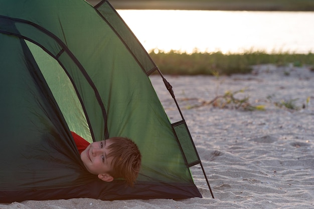 Jongen in tent lacht Kamperen met kinderen Zomerkamp voor kinderen