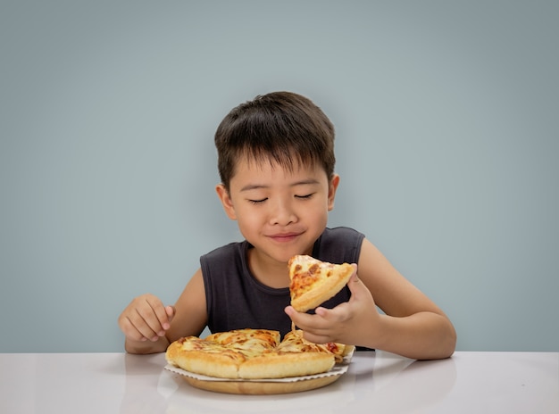 jongen is blij pizza eten met een hete kaas smelten uitgerekt op een houten plaat