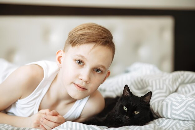 Foto jongen jongen tiener ligt op bed met beste vriend huisdier zwarte kat