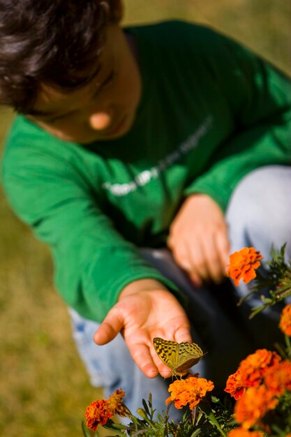 Foto jongen kijkt naar vlinders die op oranje bloemen bestuiven