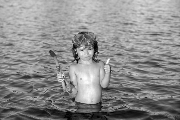 Jongen kind zwemt op het strand op zomervakantie kind in zee gelukkige kinderen zwemmen in het water kleine jongen