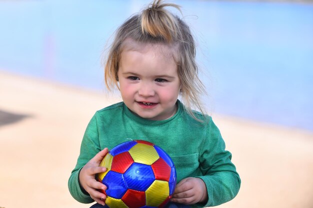 Jongen klein kind met schattig lachend blij gezicht spelen met bal op strand op zonnige zomerdag op natuurlijke...