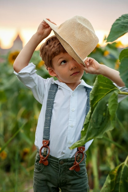 JONGEN KLEINE BOER MET EEN HOED IN EEN GEBIED VAN ZONNEBLOEMEN