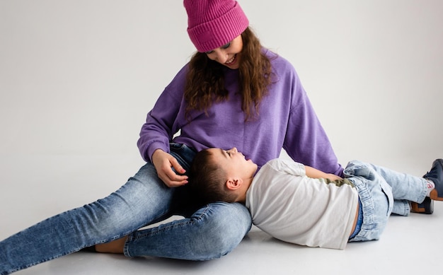 Jongen kleuter en moeder glimlach en knuffel op grijze achtergrond in fotostudio