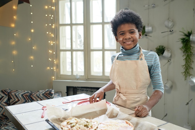 Jongen kookt pizza in de keuken