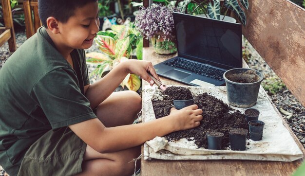 Jongen leert bloemen te kweken in het concept van vrijetijdsactiviteiten in potten