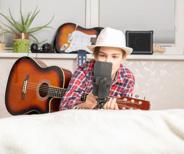 Jongen leert of haalt de vlog uit om gitaar te spelen via een videogesprek