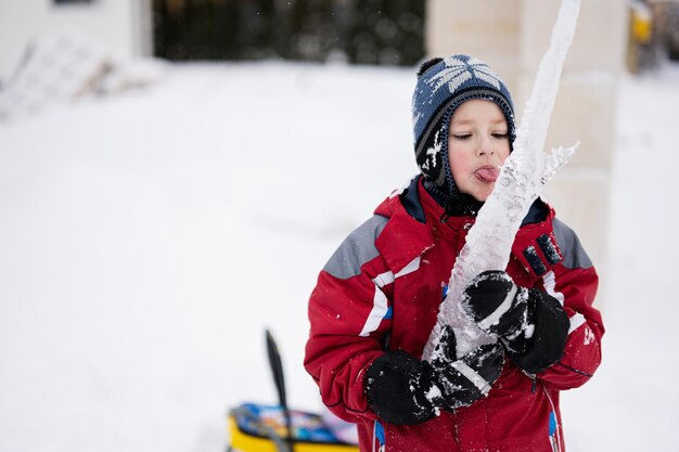 Jongen likt een ijspegel met tong in de winter