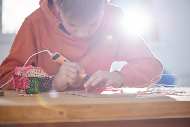 Jongen maakt volume plastic figuren met 3D-pen. STEM educatief speelgoed voor kinderen thuis en op school. Spelen en studeren