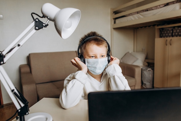 Jongen masker leren online les technologie laptop koptelefoon bluetooth internet nieuws gezondheid thuis isolatie quarantaine