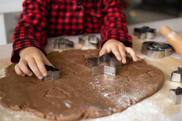 jongen meisje in rode pyjama feestelijke peperkoek koken in kerst ingerichte keuken. kerstkoekjes