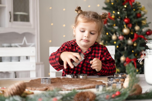 jongen meisje in rode pyjama feestelijke peperkoek koken in kerst ingerichte keuken. kerstkoekjes