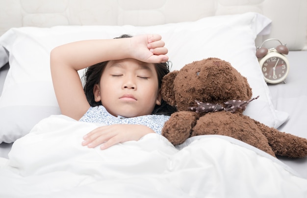 Jongen meisje slapen en ziek op het bed met beer pop