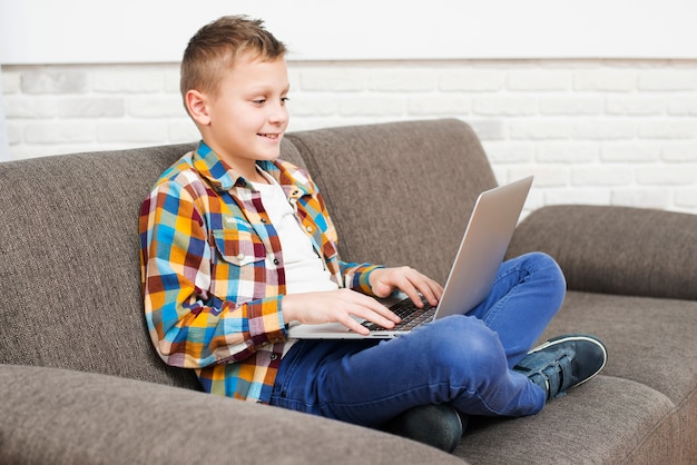 Foto jongen met behulp van laptop op de bank